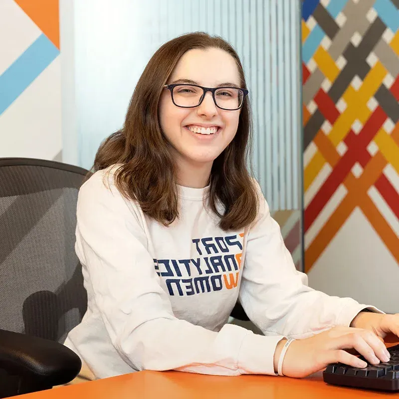 Alison Gilmore sitting at desk smiling.